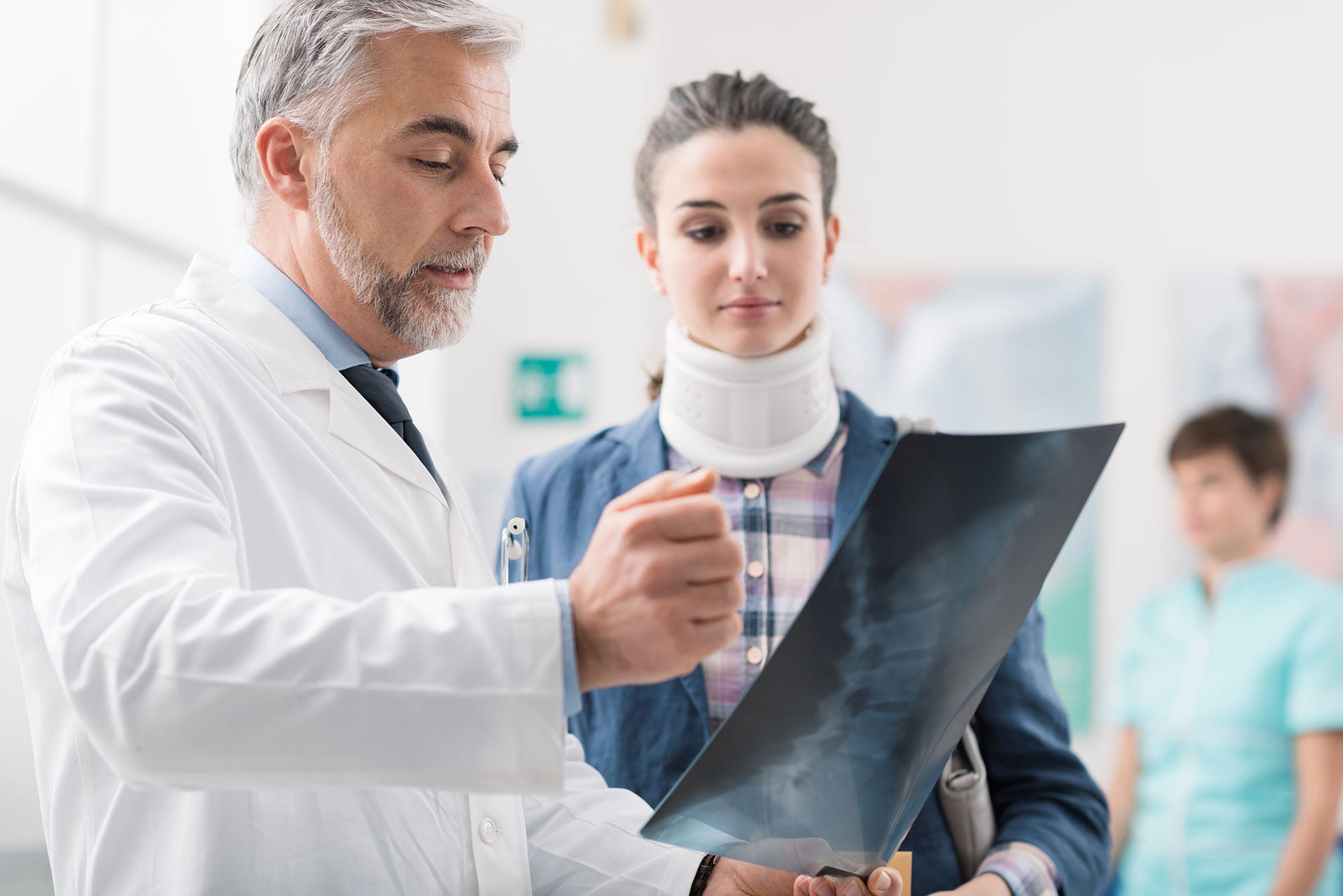 Doctor examining a woman wearing a neck brace after being injured in a car accident