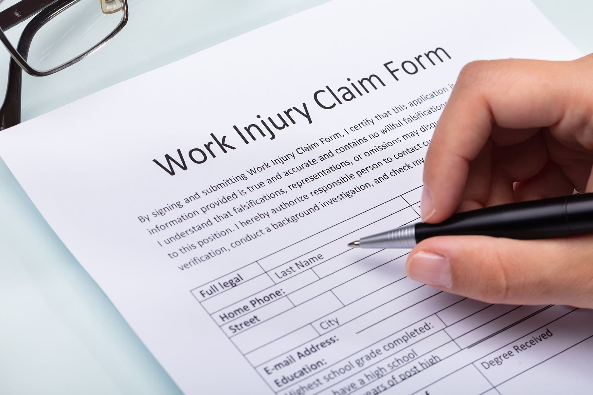 Hand filling out a work injury claim form