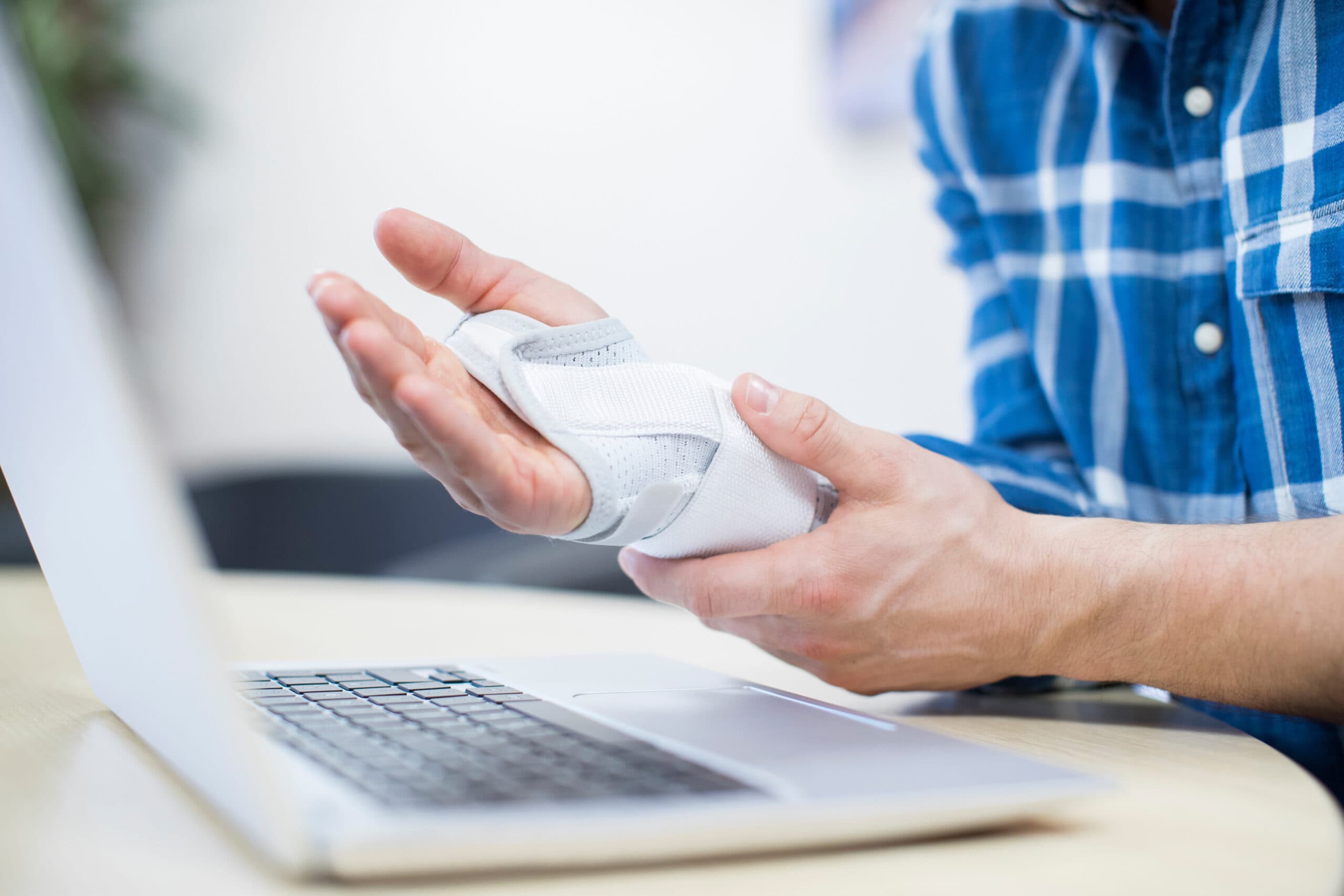 Businessman suffering from repetitive strain syndrome clutching hand that has been bandaged due to work injury