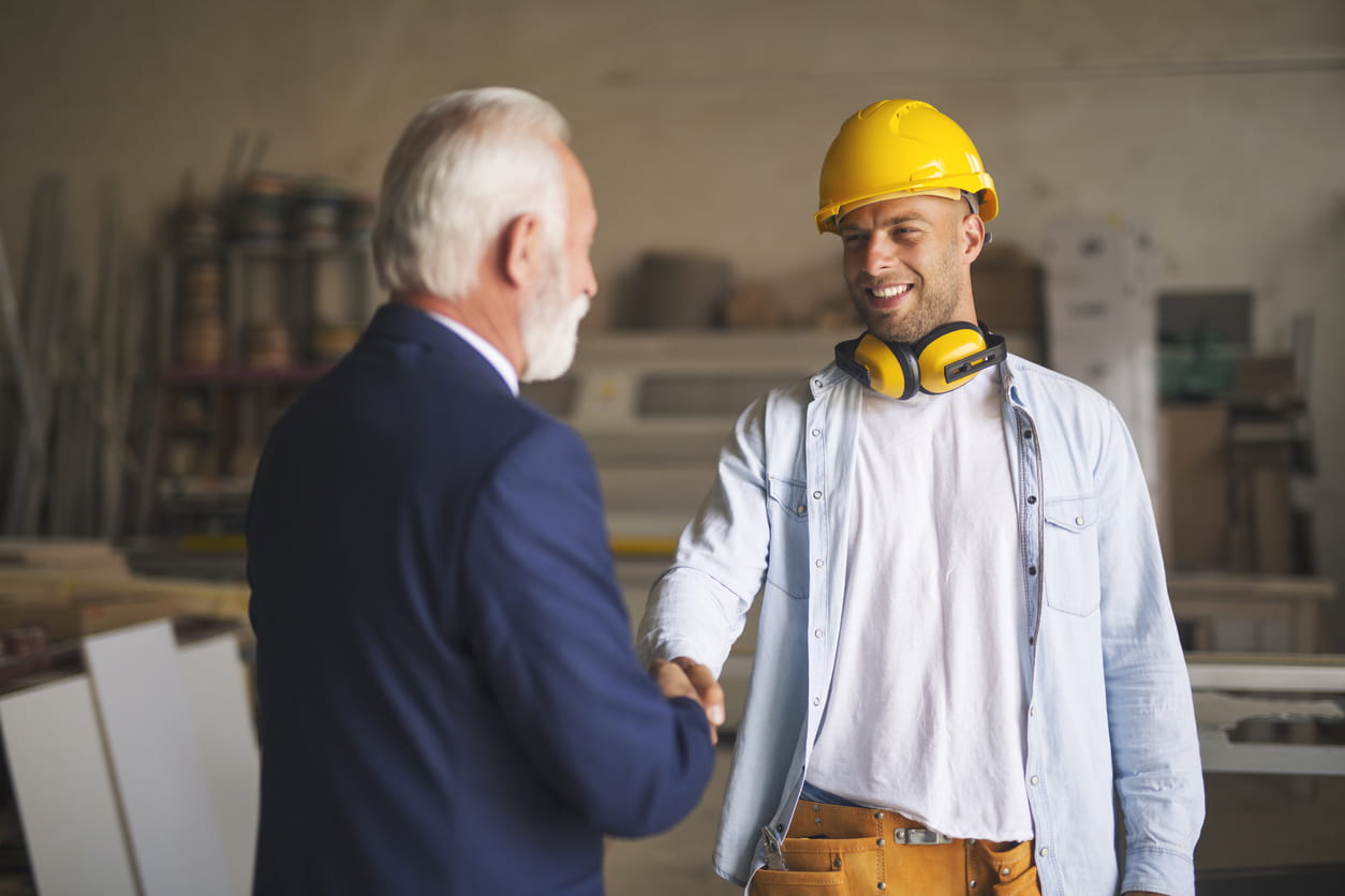 Photo of a worker on a construction site shaking hands with his lawyer