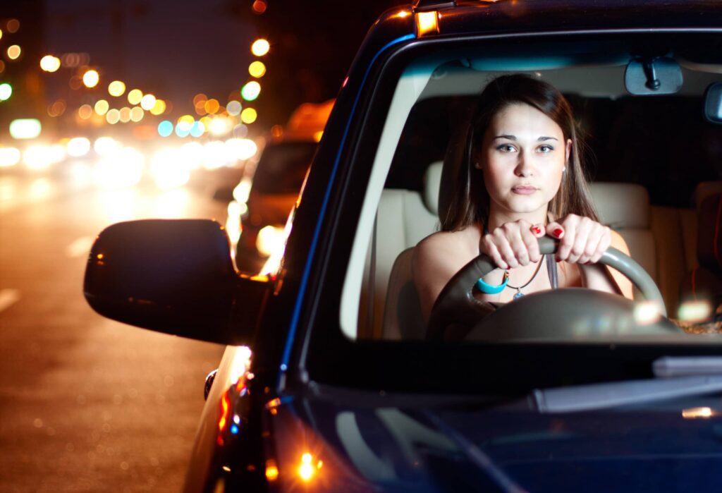 Young female driving car during the night when more serious injuries occur in road accidents