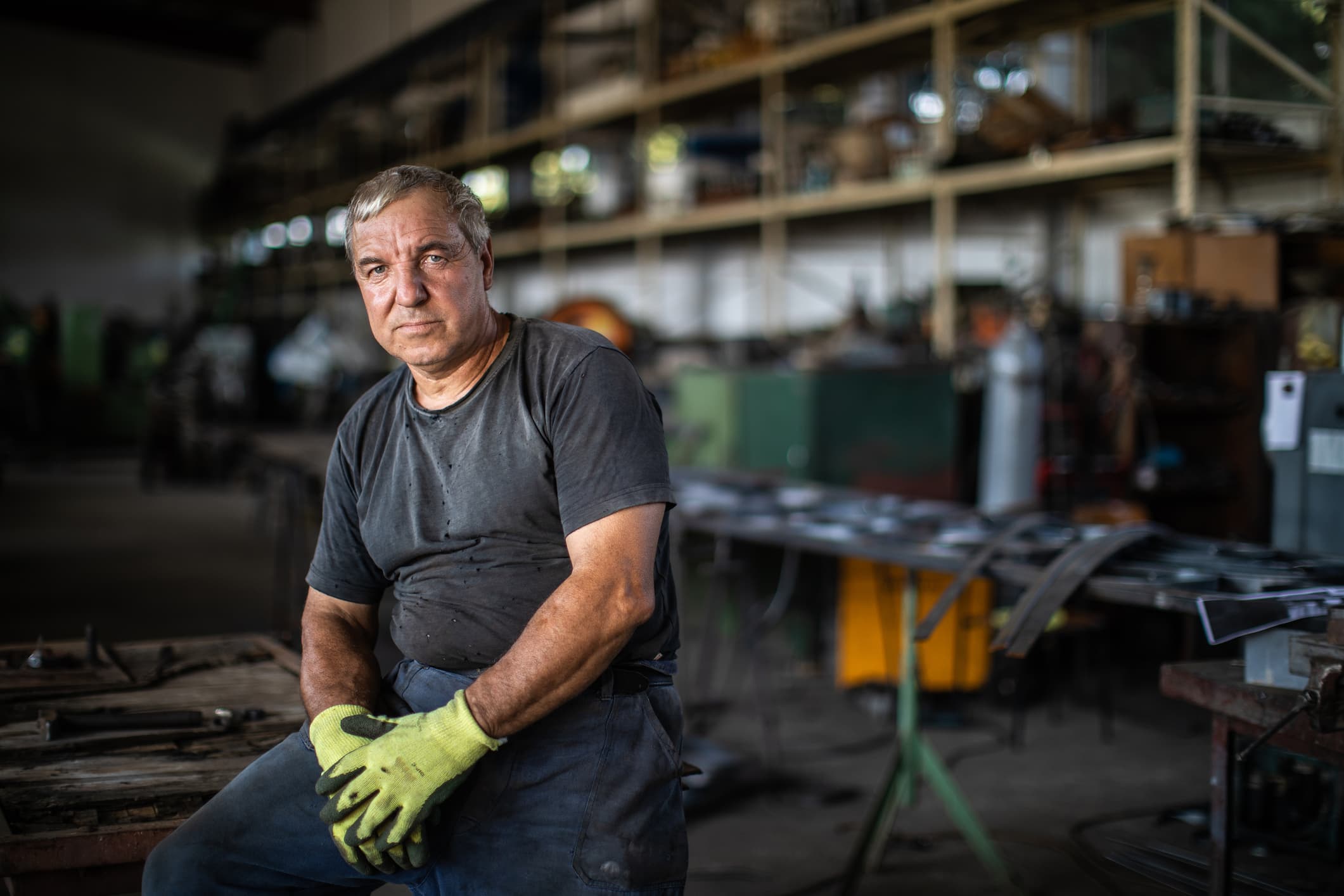 Mature male welder sitting in metalworks warehouse
