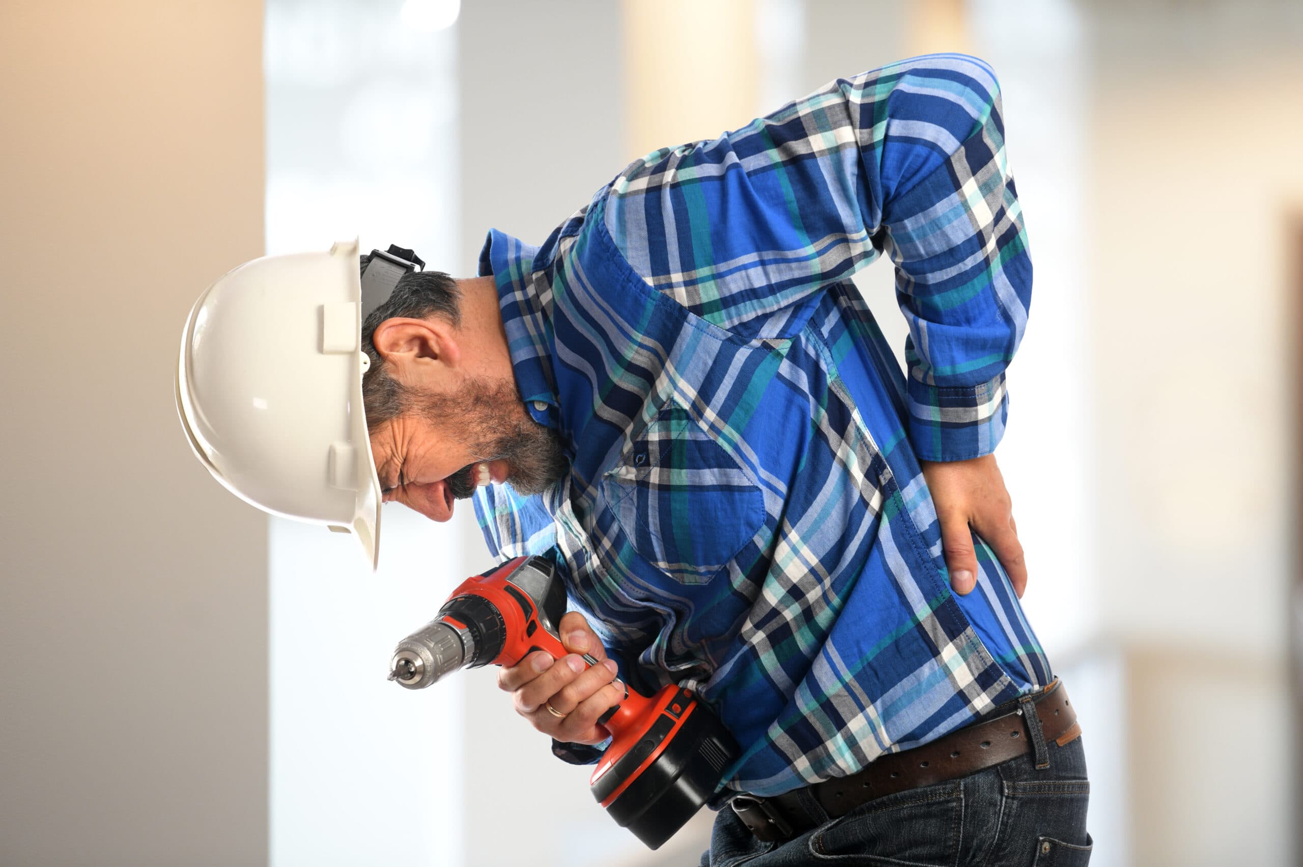 Tradie suffering from back pain holding onto lower back due to workplace personal injury