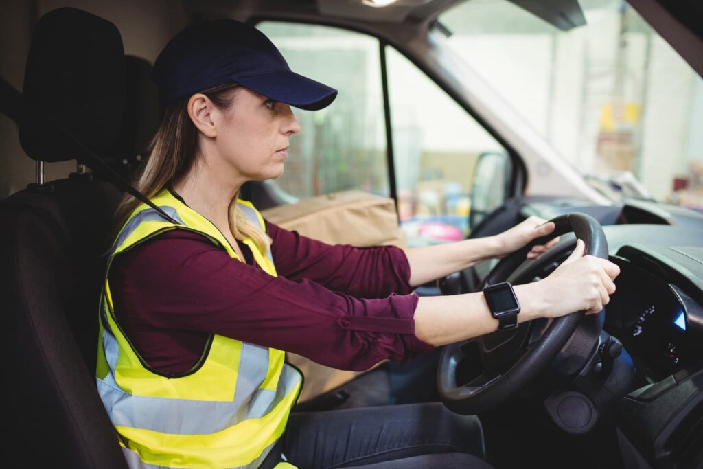 Delivery driver driving van with parcels on seat